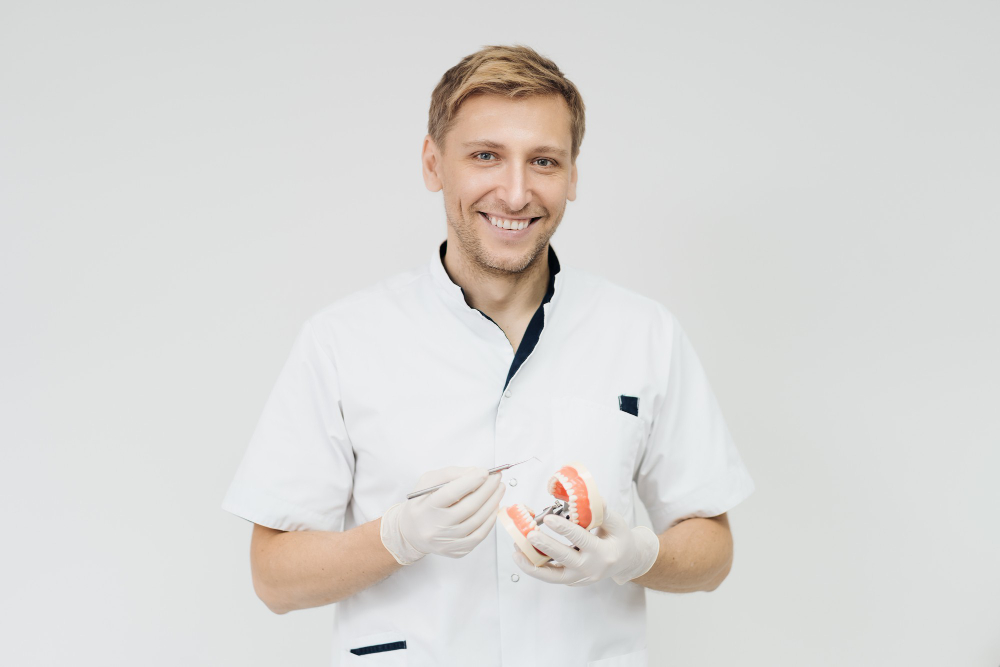 stomatologist-doctor-explaining-proper-dental-hygiene-patient-holding-sample-human-jaw